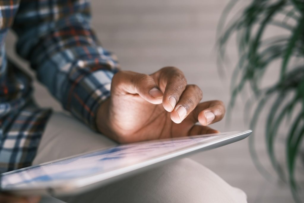 A man interacts with a tablet using their hand, focused on the screen's content