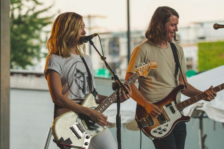 Two musicians playing guitar and singing together on stage at a lively concert