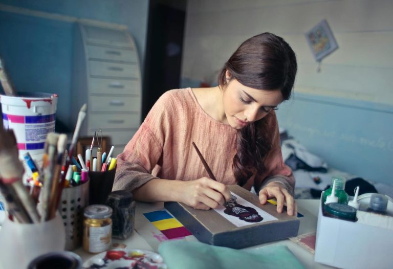 A woman drawing in her art studio, surrounded by art supplies